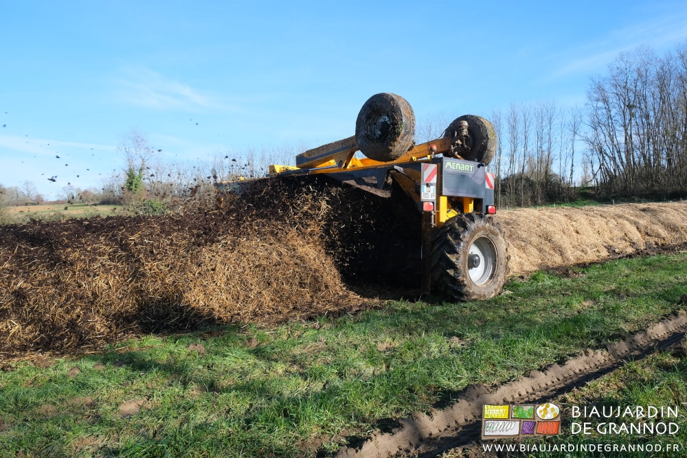 photo sous ciel bleu du retourneur qui mélange la peille en retournant le tas de fumier couvert de paille