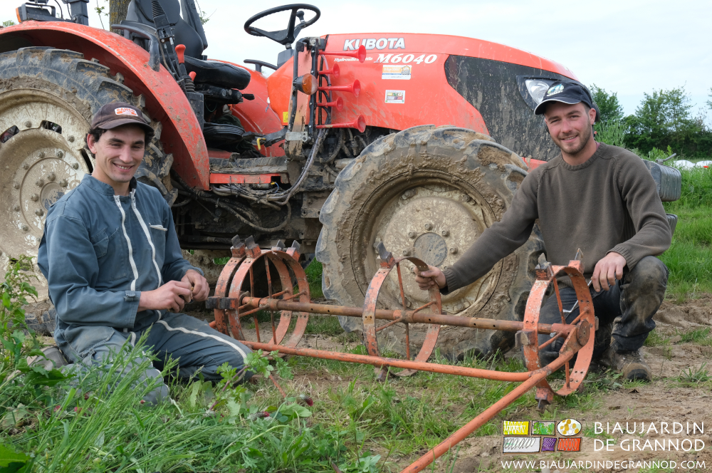 photo de Vivien et Matthieu en pause souriante réglant le rayonneur à salade près du tracteur
