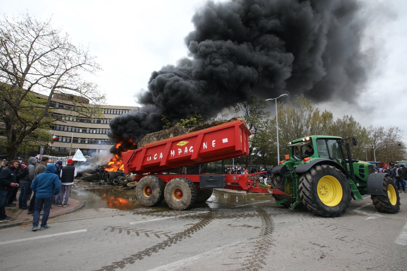 photo de benne double essieu vidant fumier, pneus, etc... entretenant un feu à grosse fumée noire