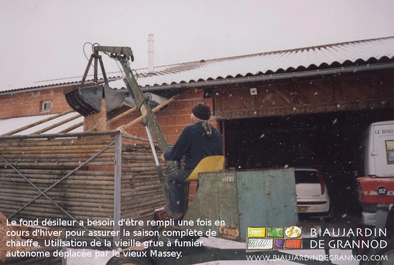 photo de Pascal remplissant le fond désileur de plaquette avec un petite grue à fumier ancienne