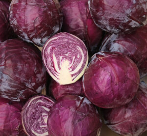 photo de choux rouges rangés en cagette bois, dont un tranché