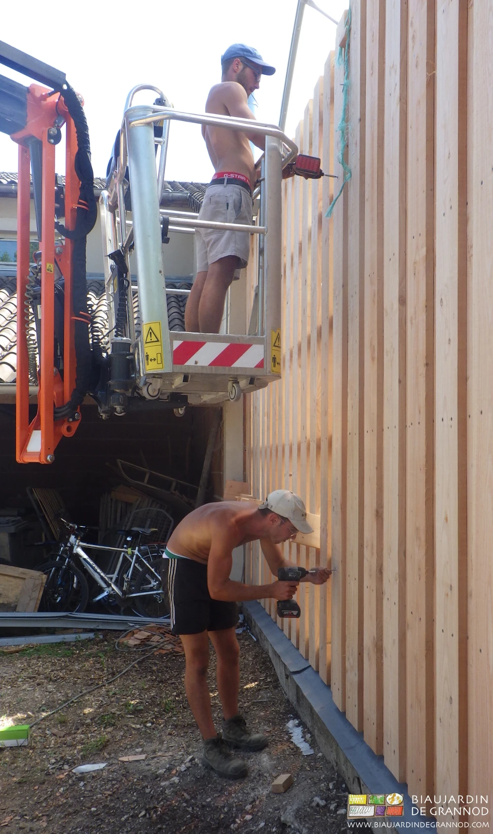 photo de la pose du bardage par Julien au sol et Matthieu sur la nacelle