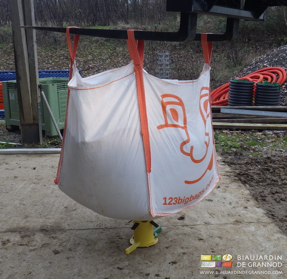 photo du big bag porté par les fourches et baissé pour le faire percer par le cône de vidage