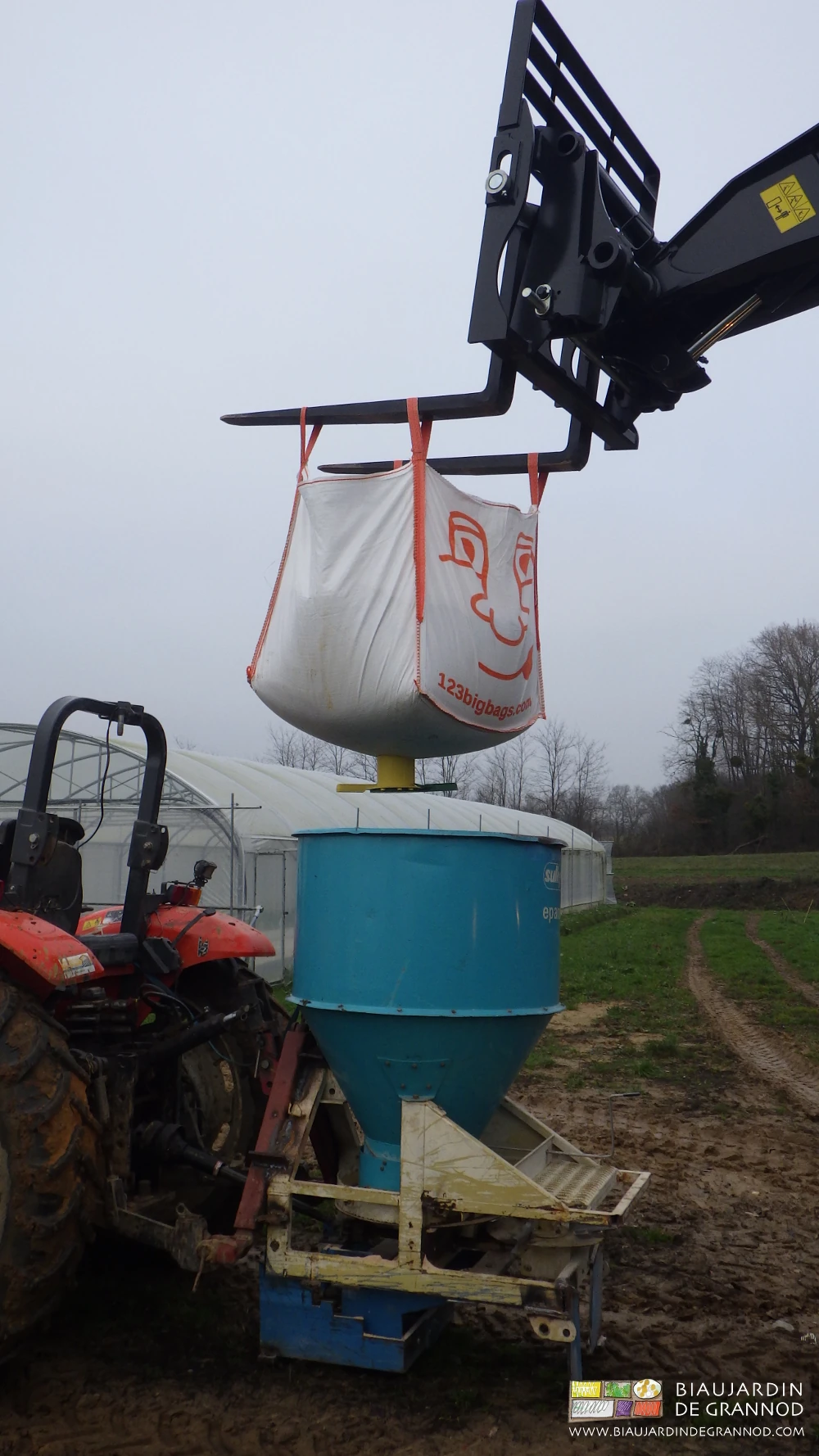 photo du big bag tenu au dessus de l'épandeur avant ouverture de la trappe du cône