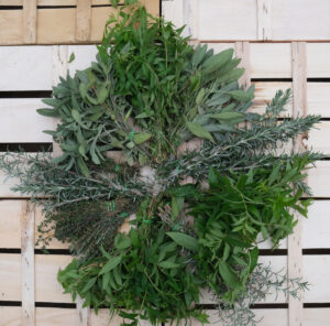 bouquets de sauge, thym, romarin, verveine rangés en rond sur une cagette bois