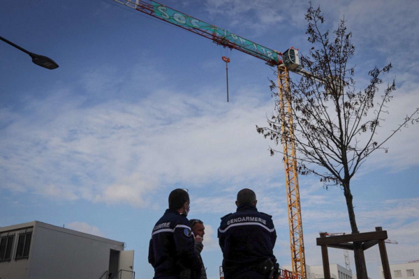 photo de 2 gendarmes au pied d'une grue immobilisée par une banderolle sur sa flèche