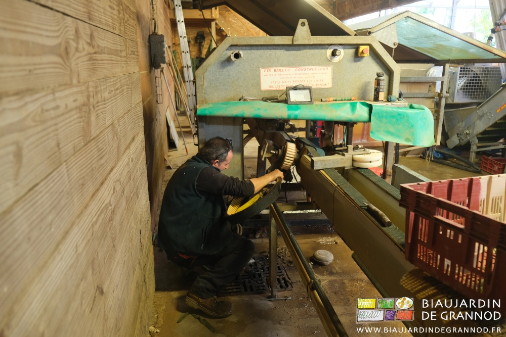 photo de Jean-Charles accroupi sus la machinepassant une des nouvelles courroies 