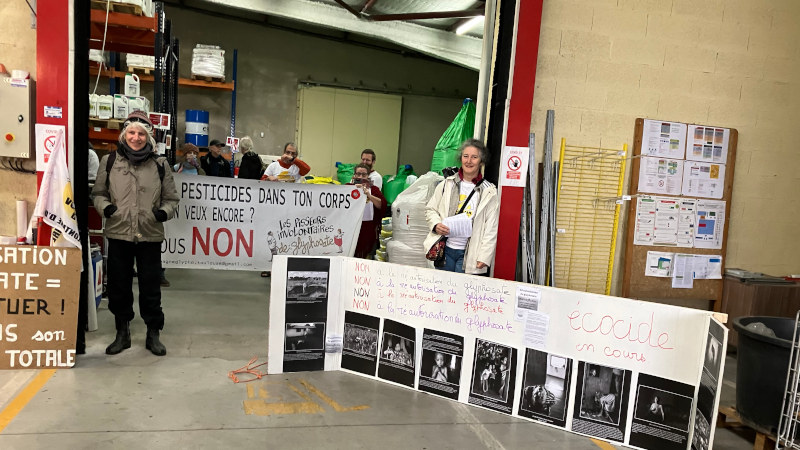 photo des Faucheureuses Volntaires et leurs banderolles dans le hangar des pesticides chimiques de synthèse