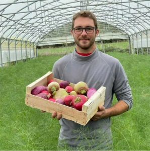 photo de Matthieu présentant des radis d'hiver de toutes couleurs en caisse bois