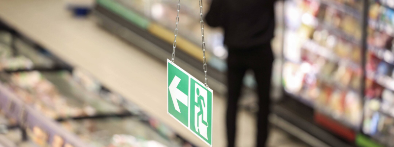 copie écran Public Sénat panneau de sécurité blanc vert issue de secours dans une grande surface